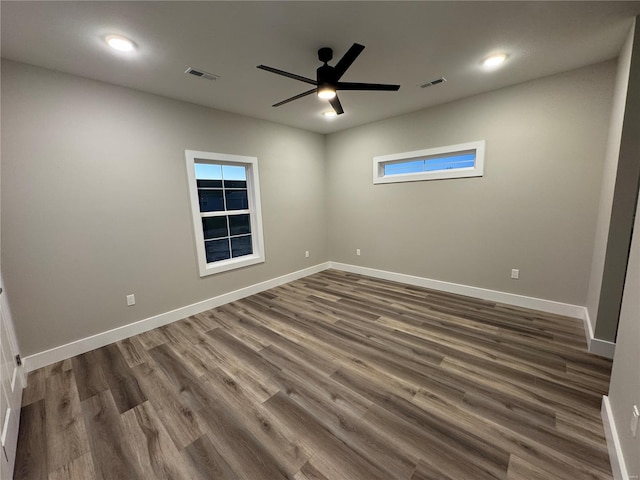 unfurnished room featuring dark wood finished floors, visible vents, and baseboards
