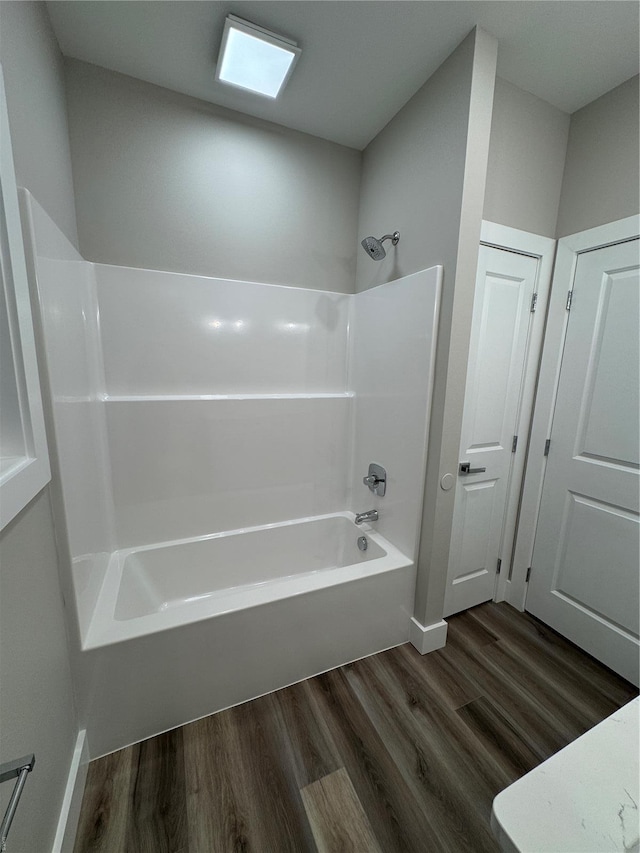 full bath featuring bathing tub / shower combination, wood finished floors, and baseboards