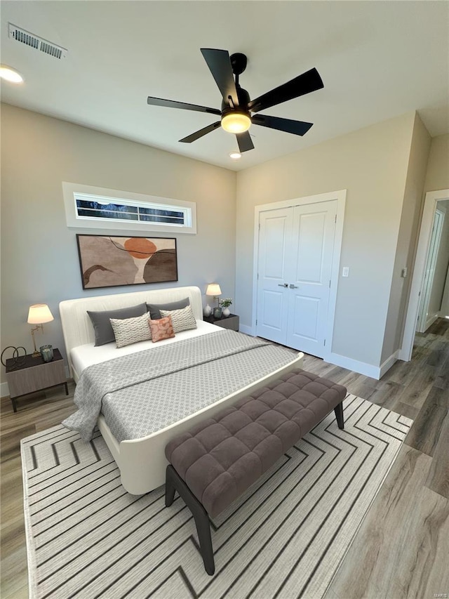 bedroom with a ceiling fan, visible vents, light wood-style flooring, and baseboards