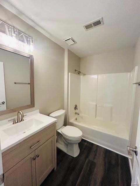 bathroom with vanity, toilet, tub / shower combination, wood finished floors, and visible vents