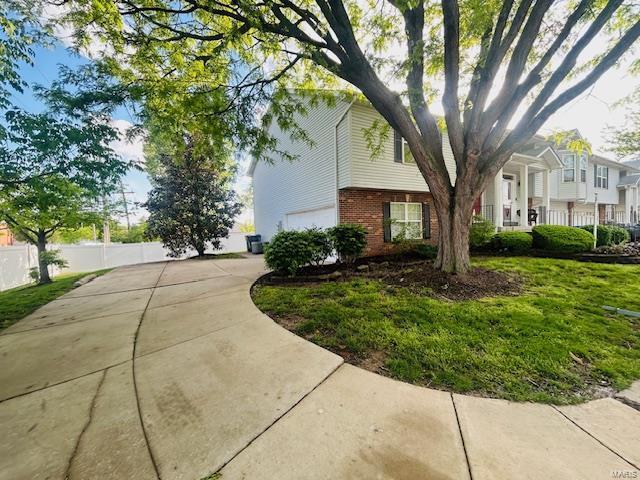 view of property exterior with fence, concrete driveway, a garage, and brick siding