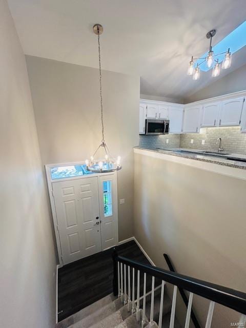 foyer entrance featuring a notable chandelier and vaulted ceiling