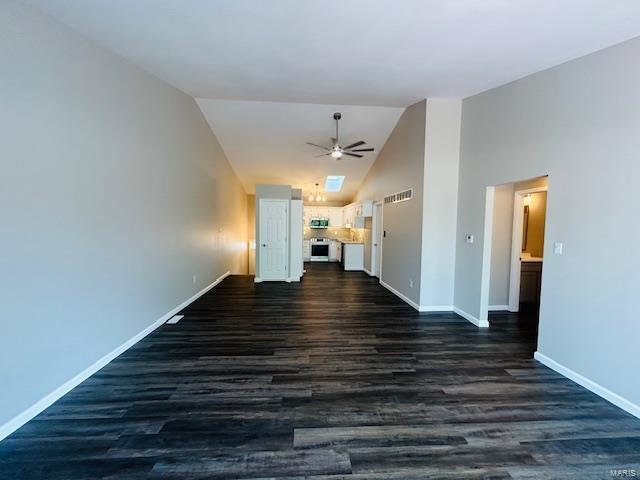 unfurnished living room featuring a ceiling fan, baseboards, visible vents, and dark wood finished floors