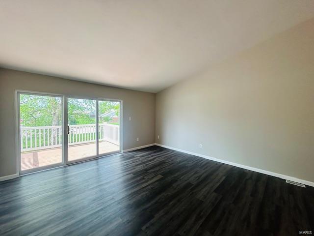 unfurnished room featuring baseboards, dark wood-style flooring, and visible vents