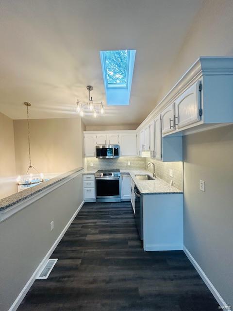 kitchen featuring visible vents, tasteful backsplash, a sink, appliances with stainless steel finishes, and a skylight