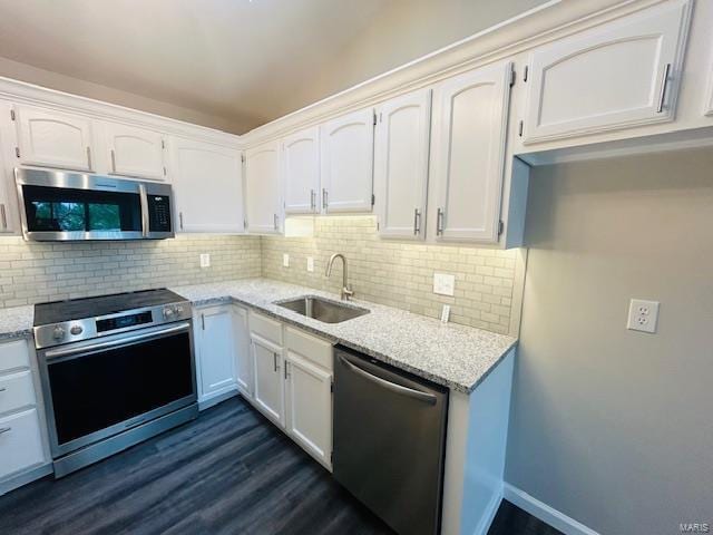 kitchen featuring tasteful backsplash, light stone countertops, a sink, stainless steel appliances, and dark wood-type flooring