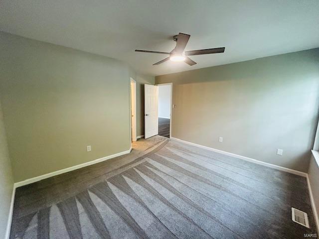 carpeted spare room with visible vents, a ceiling fan, and baseboards