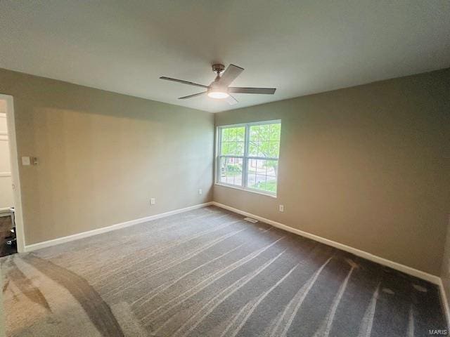 empty room featuring baseboards, ceiling fan, and dark carpet