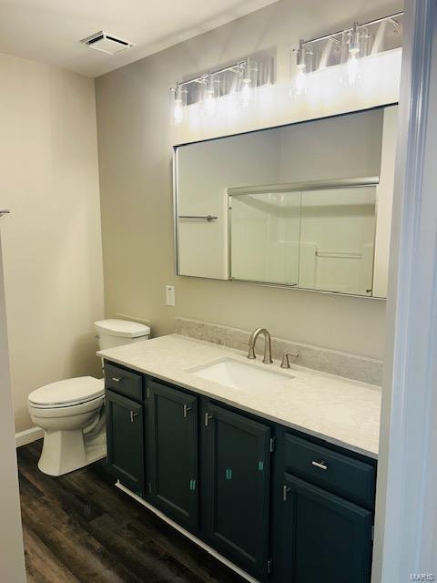 bathroom featuring toilet, visible vents, wood finished floors, and vanity