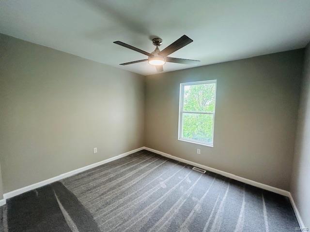 empty room featuring baseboards, a ceiling fan, dark colored carpet, and visible vents