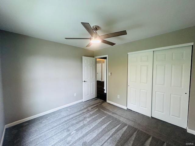 unfurnished bedroom with baseboards, ceiling fan, a closet, and dark colored carpet