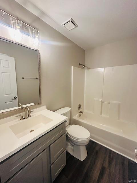full bathroom with visible vents, vanity, tub / shower combination, wood finished floors, and toilet