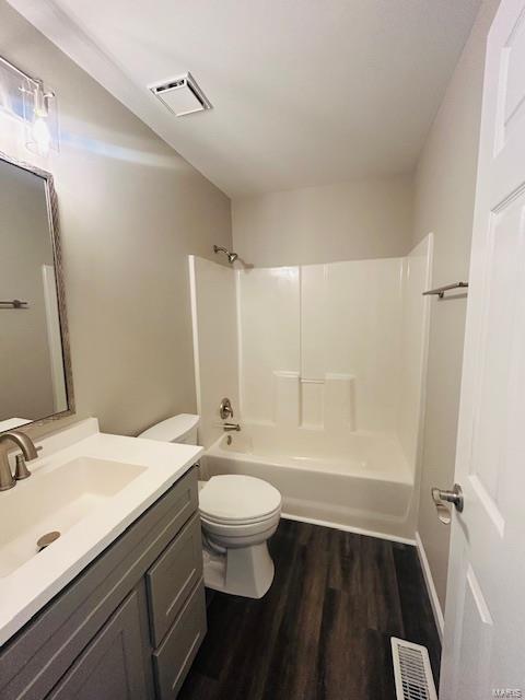 full bath featuring visible vents, vanity, wood finished floors, toilet, and bathtub / shower combination