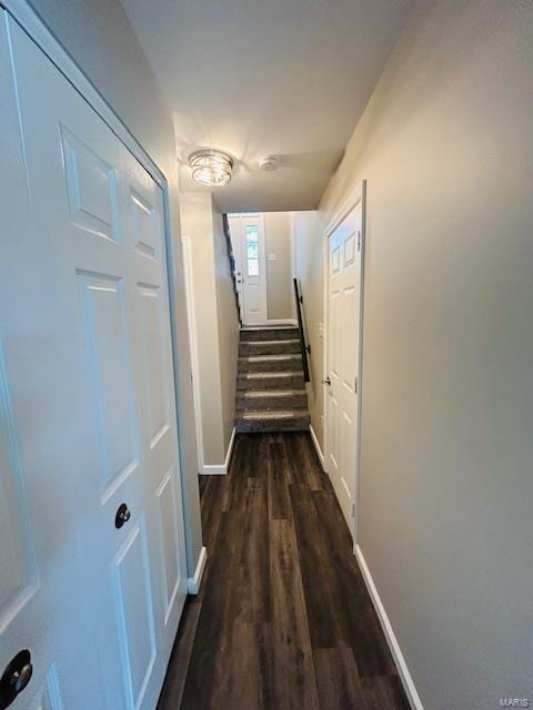 hallway featuring baseboards and dark wood-type flooring