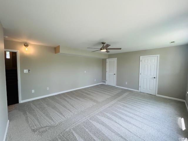 spare room with baseboards, ceiling fan, and light colored carpet