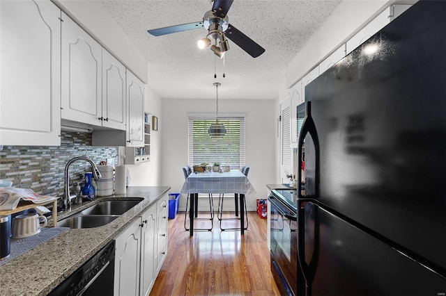 kitchen featuring ceiling fan, a sink, a textured ceiling, backsplash, and black appliances