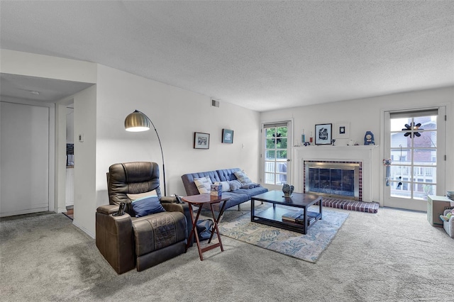 living room featuring visible vents, carpet flooring, a textured ceiling, and a fireplace
