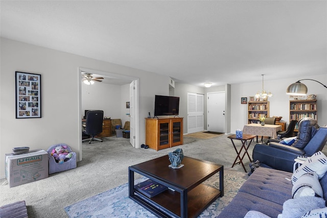 living area featuring carpet and ceiling fan with notable chandelier