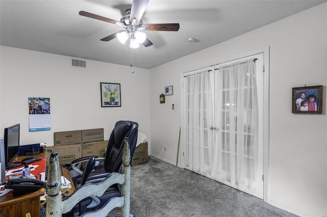 office space featuring carpet floors, a ceiling fan, a textured ceiling, and visible vents
