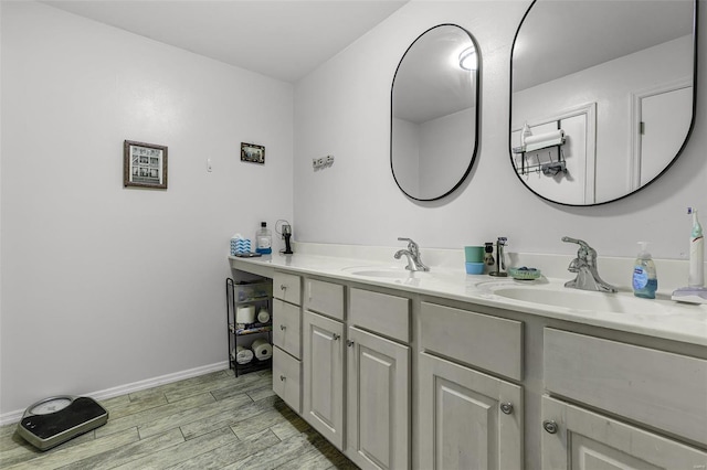 bathroom featuring double vanity, baseboards, a sink, and wood finished floors