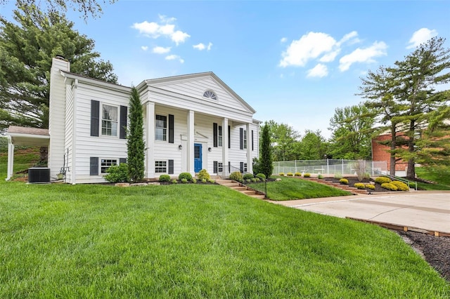 view of front of property with fence, a chimney, cooling unit, and a front lawn