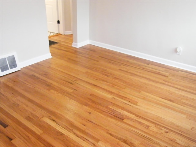 empty room featuring baseboards, light wood finished floors, and visible vents