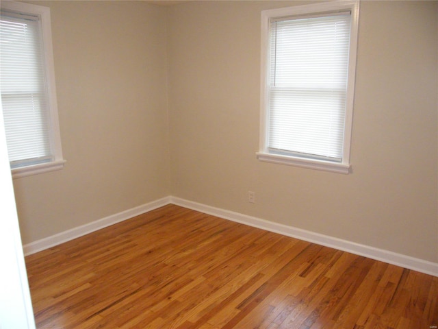 empty room with baseboards, plenty of natural light, and light wood-type flooring