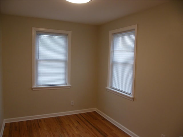 unfurnished room featuring plenty of natural light, baseboards, and wood finished floors