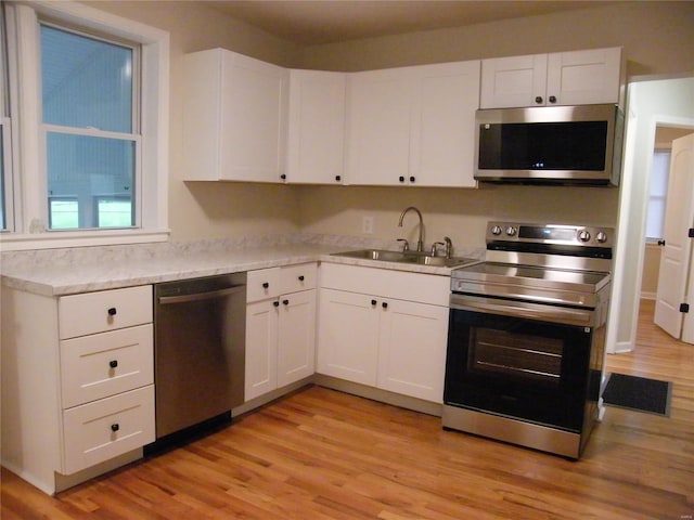 kitchen with visible vents, light countertops, white cabinets, a sink, and stainless steel appliances