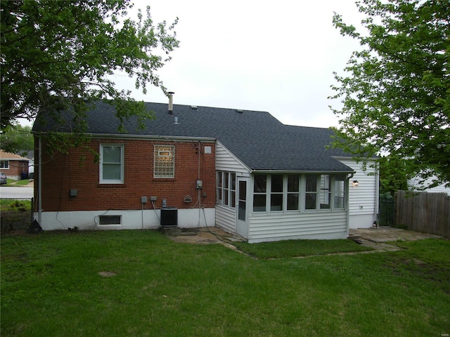 back of house featuring a lawn, fence, and a shingled roof