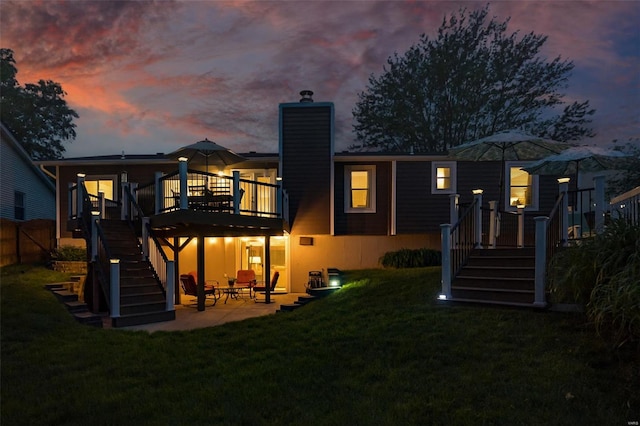 rear view of property with a deck, a chimney, a patio area, and stairway