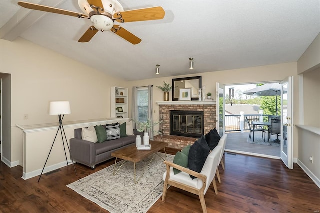 living area with ceiling fan, a fireplace, baseboards, vaulted ceiling with beams, and wood finished floors