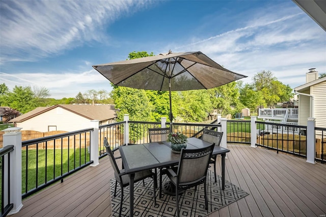 wooden terrace featuring outdoor dining area, an outdoor structure, a shed, and a yard