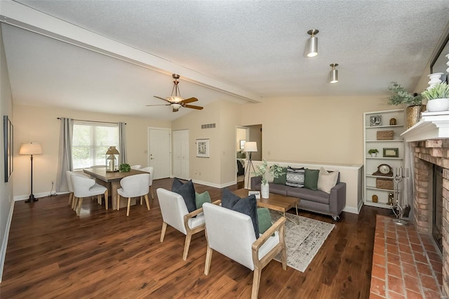 living area featuring a ceiling fan, visible vents, a brick fireplace, wood finished floors, and lofted ceiling with beams