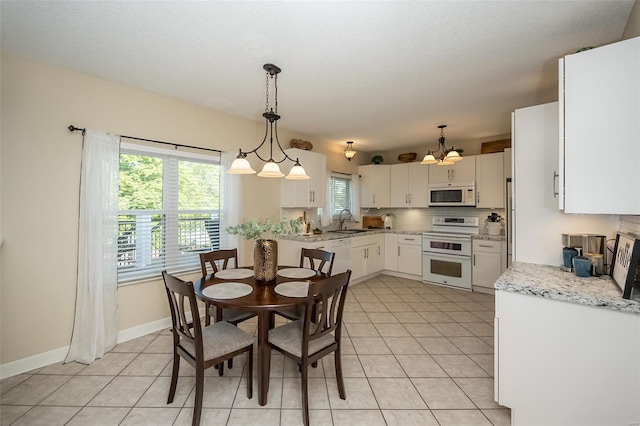 dining area with baseboards, a notable chandelier, and light tile patterned floors