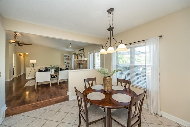 dining space with a ceiling fan, baseboards, vaulted ceiling, and light tile patterned floors