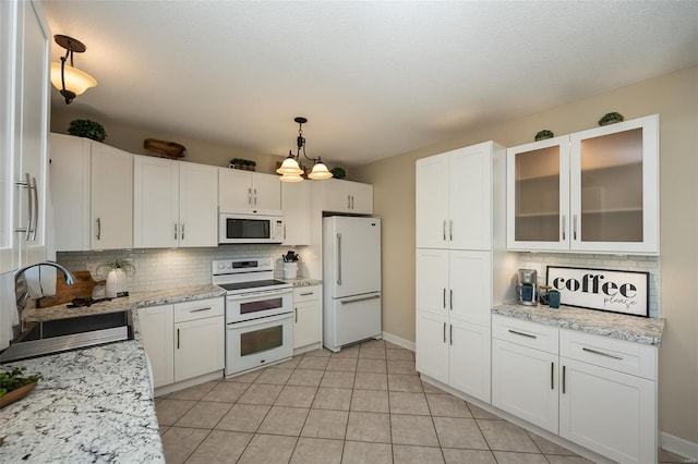 kitchen with white appliances, white cabinets, decorative backsplash, and a sink