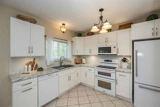 kitchen featuring tasteful backsplash, a sink, light tile patterned floors, white appliances, and white cabinetry