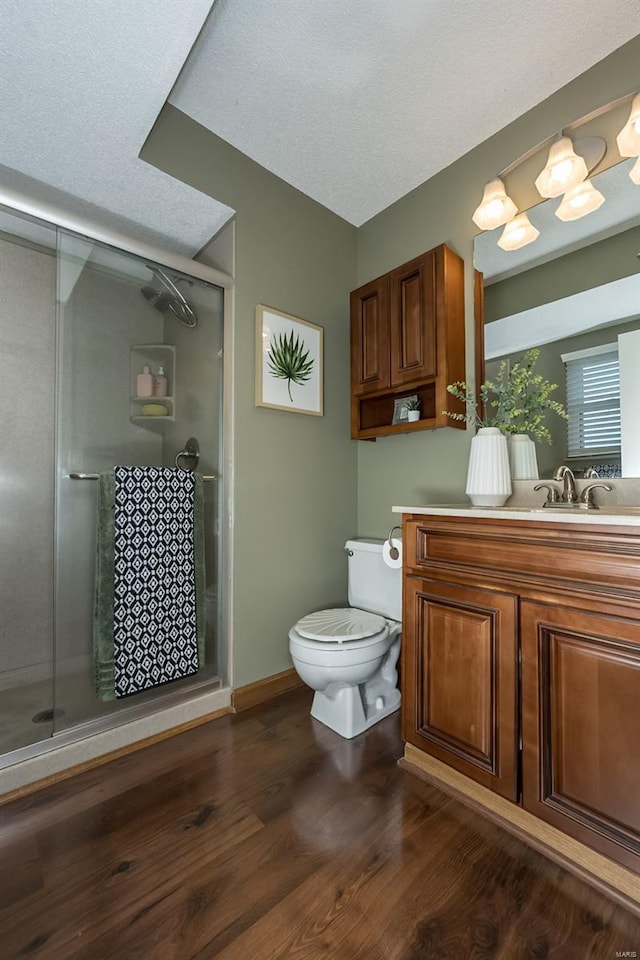 full bathroom with a stall shower, wood finished floors, vanity, baseboards, and toilet