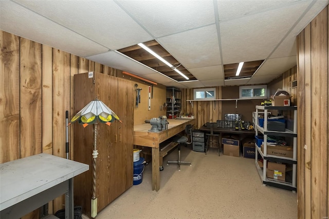 office area featuring a paneled ceiling, wooden walls, and a workshop area