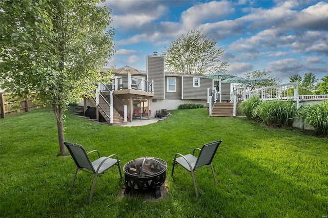 exterior space featuring a wooden deck, a patio area, stairway, fence, and an outdoor fire pit