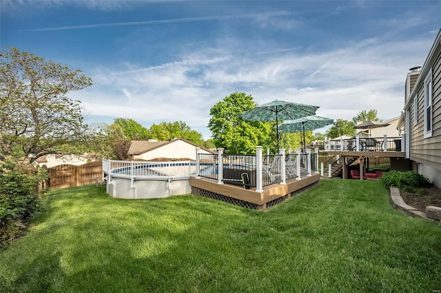 view of yard featuring a deck, fence, and an outdoor pool