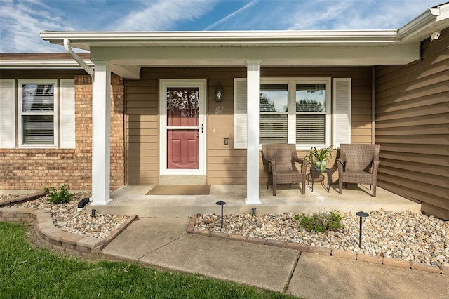doorway to property with a porch and brick siding