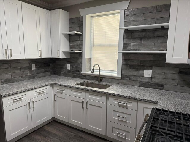 kitchen featuring a sink, tasteful backsplash, open shelves, and white cabinetry