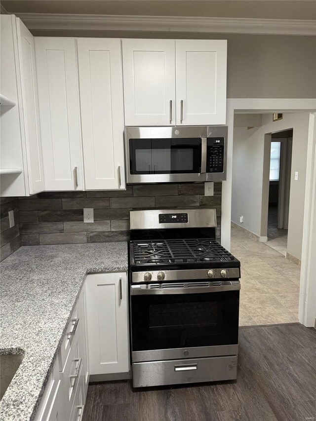 kitchen featuring appliances with stainless steel finishes, ornamental molding, backsplash, and white cabinets