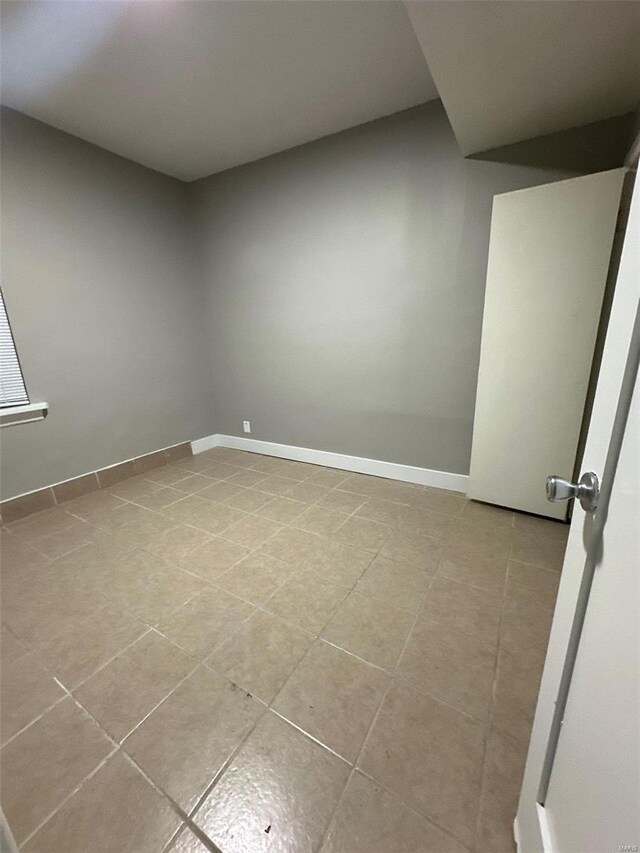 spare room with baseboards and light tile patterned flooring