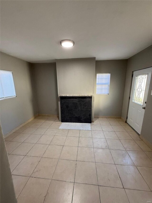 unfurnished living room with baseboards, light tile patterned floors, and a fireplace