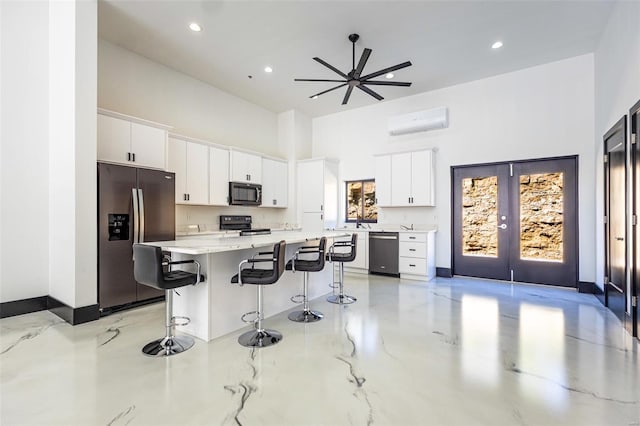 kitchen featuring a breakfast bar, a high ceiling, a wall mounted AC, white cabinets, and black appliances