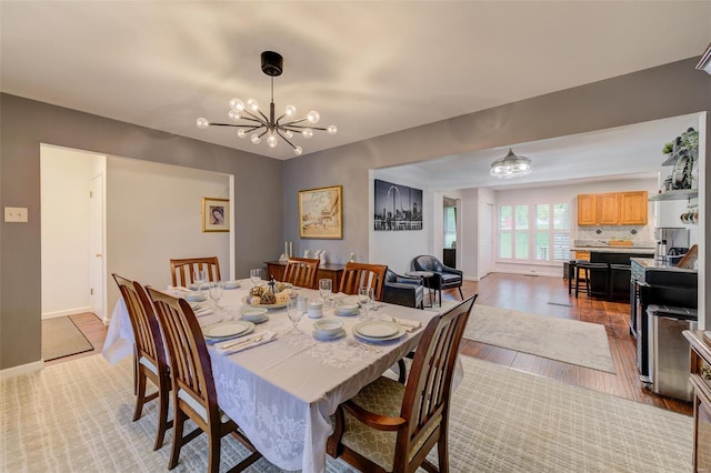 dining area featuring light wood-type flooring, baseboards, and a notable chandelier