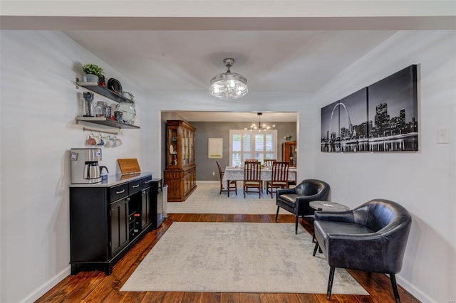 living area with dark wood finished floors, baseboards, and a notable chandelier